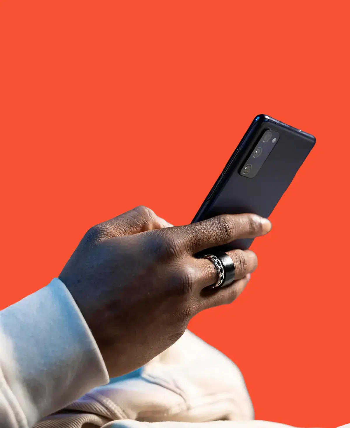 A hand holding a smartphone against an orange background