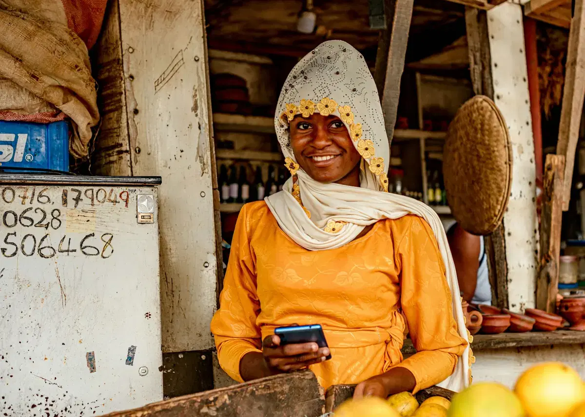 A trader checking her phone at her fruit stall