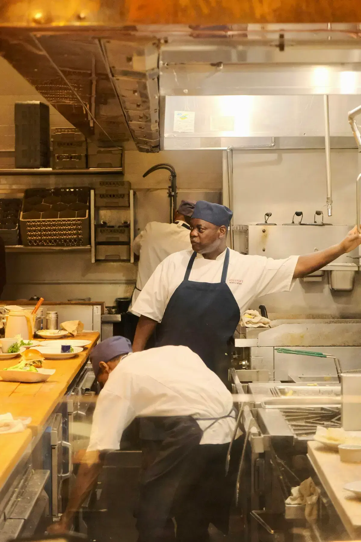 A chef directing service in a busy restaurant kitchen