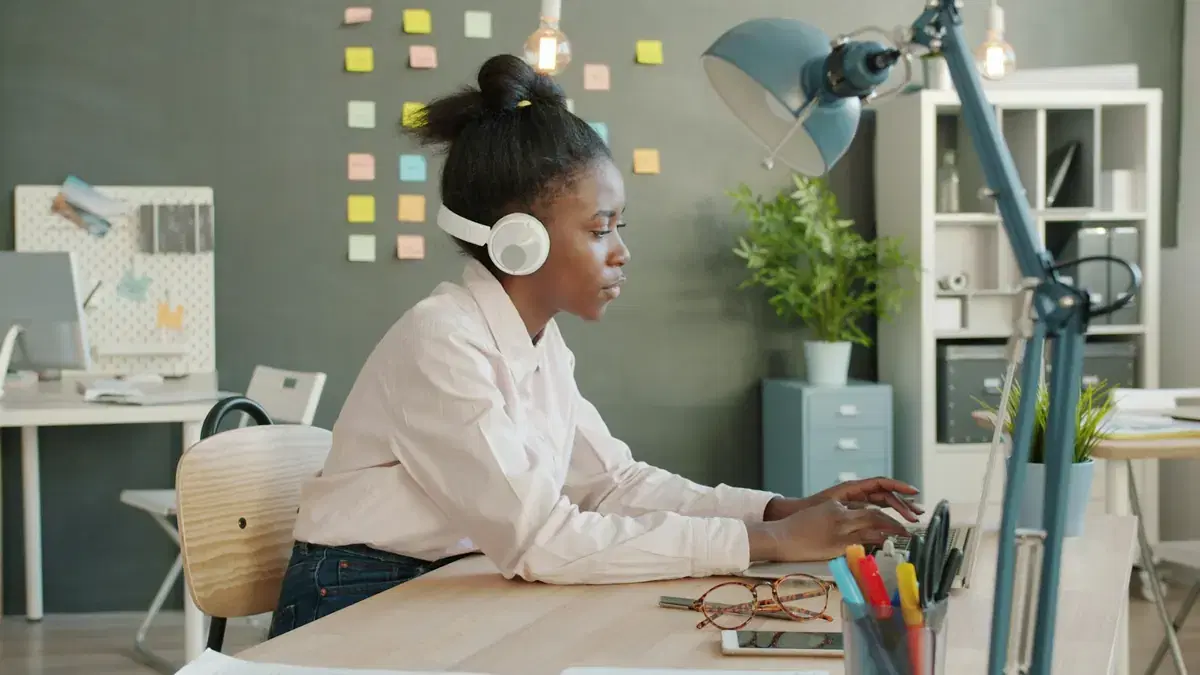 A support specialist wearing headphones while working at her desk