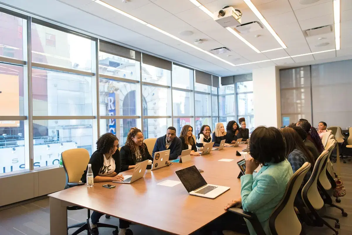 A team seated around a long boardroom table with laptops