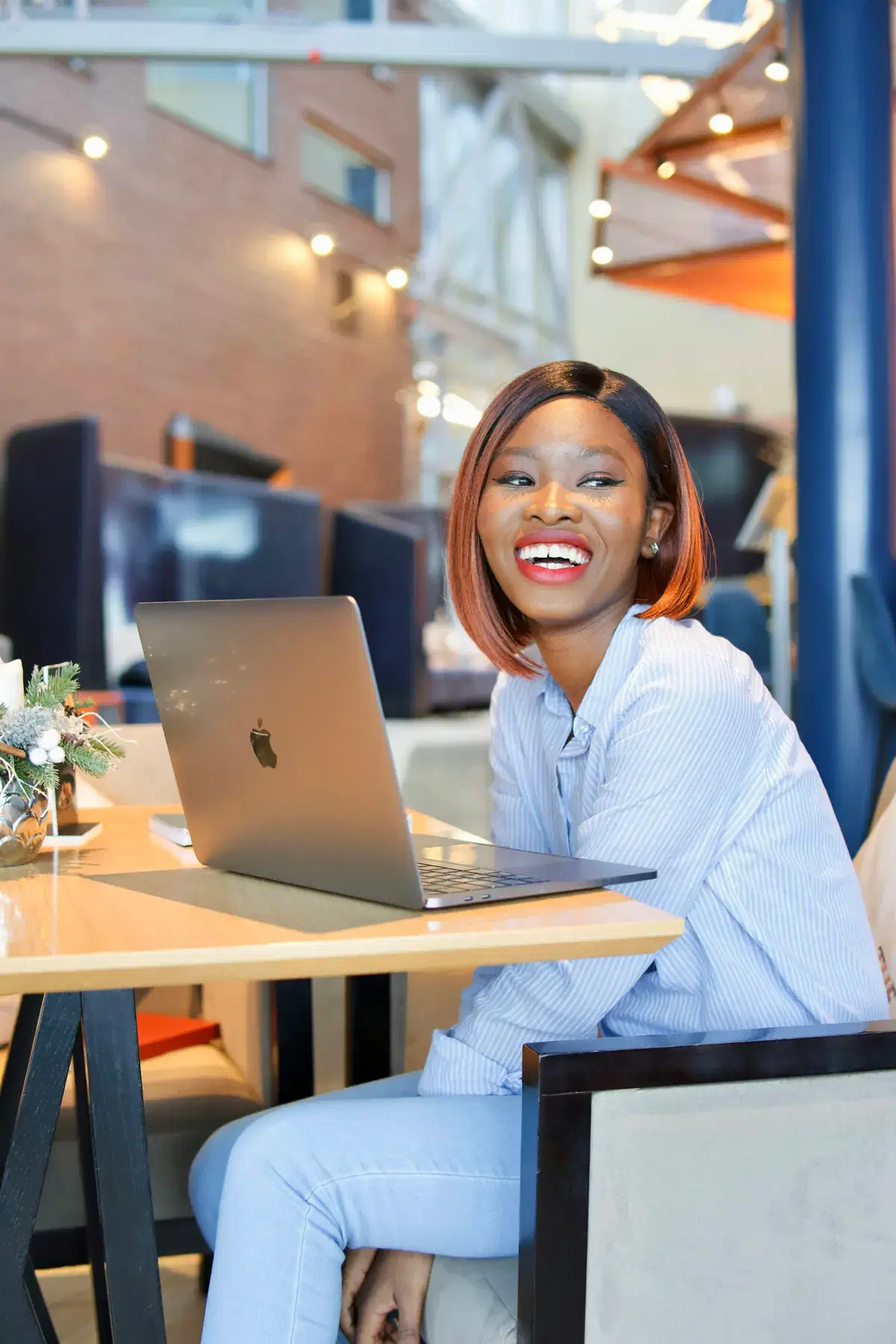 A woman smiling at her desk while working on a laptop